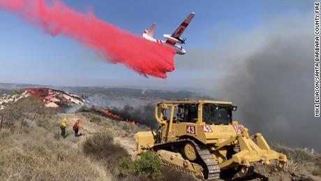 As a bulldozer digs a fire mine, a foot fire plane drops the Bose-check by the Vandenberg Air Force Base near 110 acres.