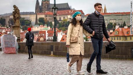 Tourists walk across the medieval Charles Bridge in Prague as the Czech Republic faces a record increase after previously keeping the numbers low.