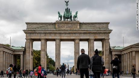 Tourists walk through the Brandenburg Gate in Berlin, Germany on October 12 as meetings are limited to 10 people and a curfew is imposed at 11pm in many regions.