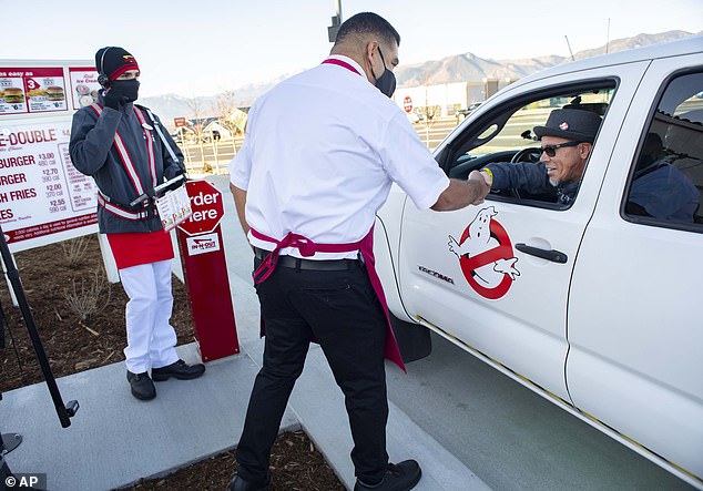 Colorado Springs in-n-out manager Saul Ariola (in white) shakes hands with Ken Wiccini (right), the first person to wait in line at the front line on Tuesday