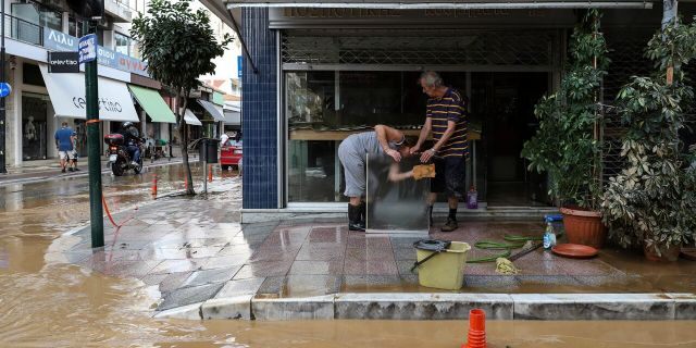 Residents clean a glass sheet near a flooded street after a storm in Kardashian on Saturday, September 19, 2020.