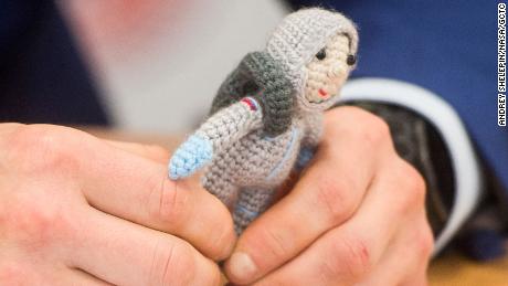 Expedition 64 crew member Sergei Good-Sverkov holds a knitted astronaut named Yuri, made by his wife Olga.