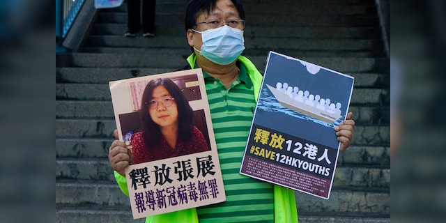 A pro-democracy activist holds a billboard in Hong Kong, outside the Chinese federal government's liaison office, with a picture of Chinese citizen journalist Zhang Jan.  (AP Photo / Qin Cheung)