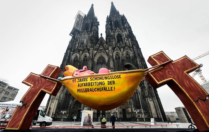 A festival car with a picture of a sleeping cardinal in front of the Cathedral of Cologne on the day the investigation report was released and the text '11 years of brutal handling of abuse cases'.