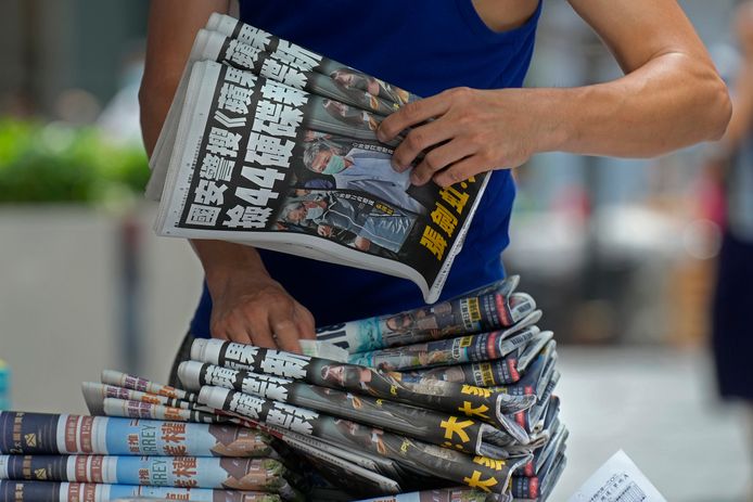 A street vendor with a large bundle of copies of the Apple Daily.