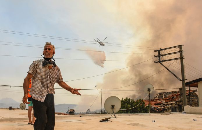 A resident of the village of Sirtkoy, near Manavgat in Antalya province, with a firefighting helicopter in the background.