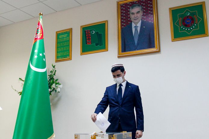 A man votes on March 12, 2022. Above him hangs a portrait of dictator Gurbanguly Berdimukhamedov.