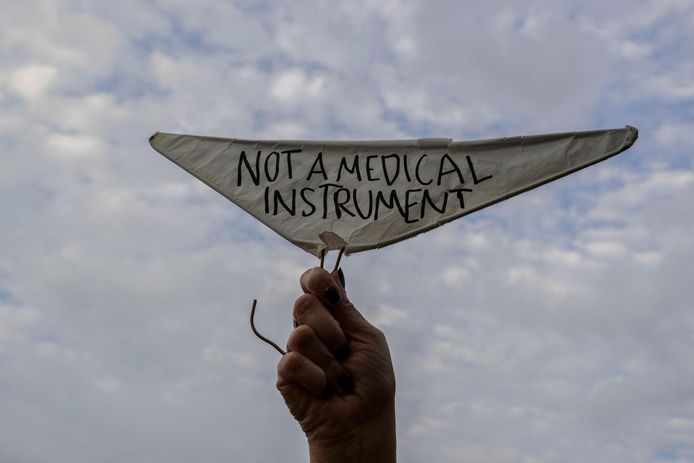 A man holds a metal coat hanger marked 'Not a medical device'.  Now that abortion is banned in states like Missouri, there are fears that illegal and dangerous abortions involving metal hangers will become more common.